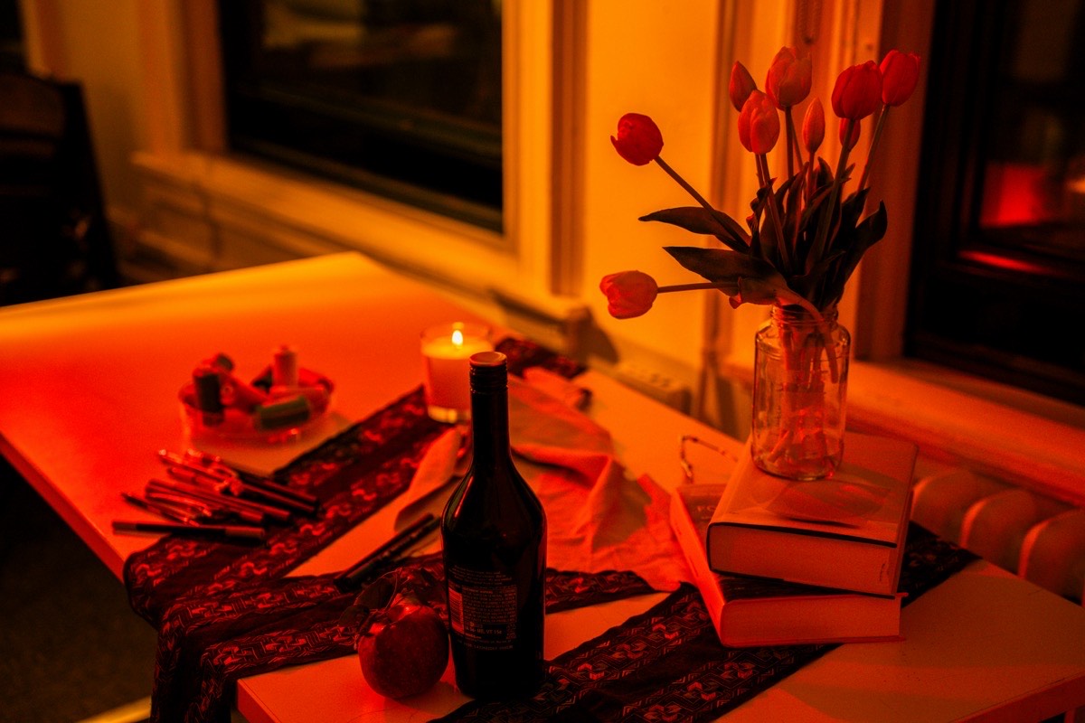 A glass of red wine on a candlelit dinner table with fresh flowers