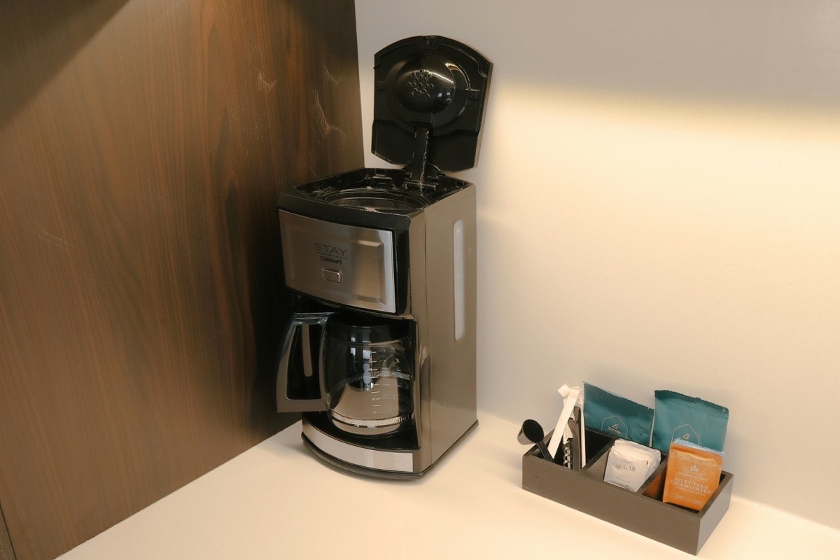 Tea and sugar packets arranged beside a coffee maker on a kitchen counter