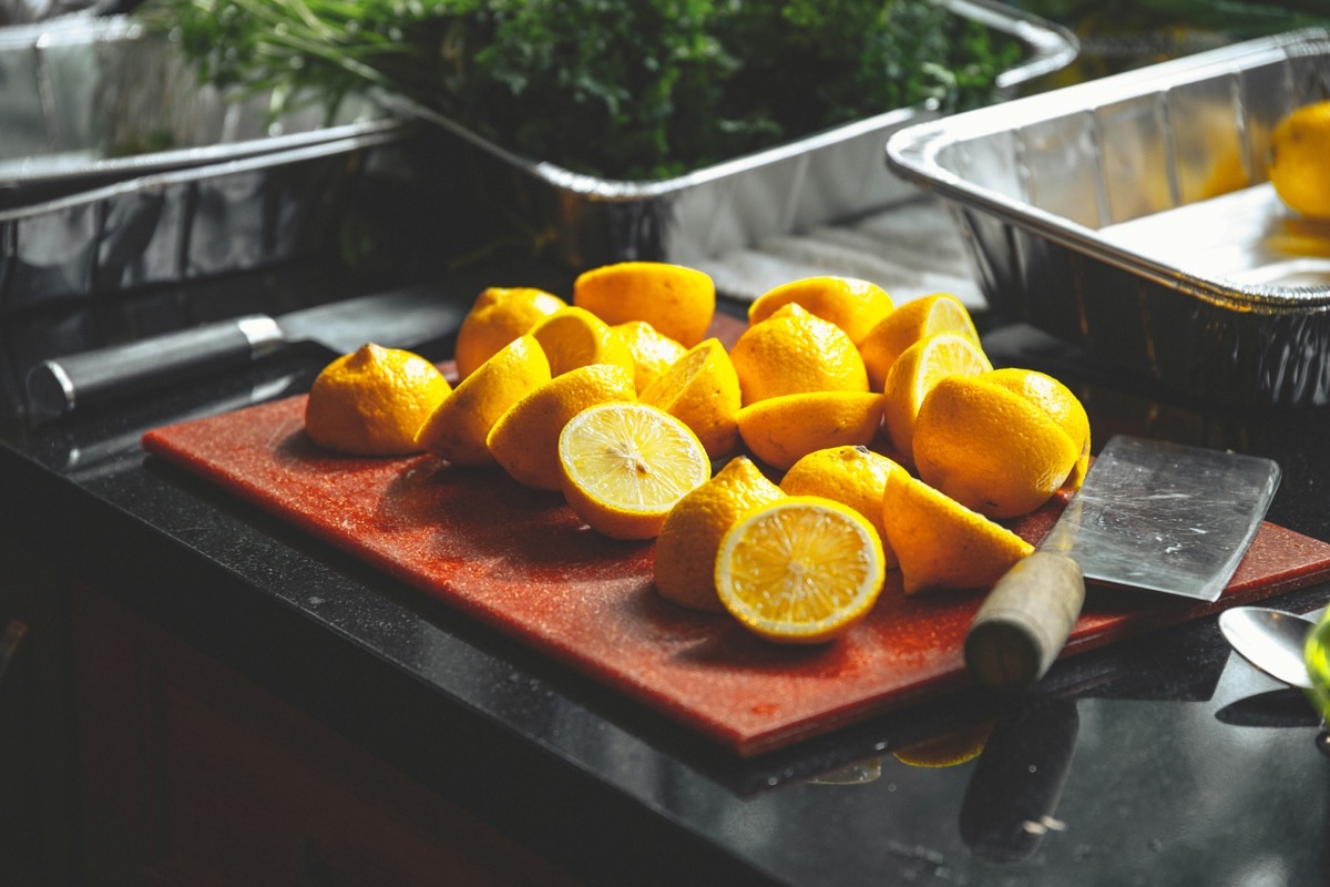 Sliced yellow lemons on a wooden cutting board next to a kitchen knife