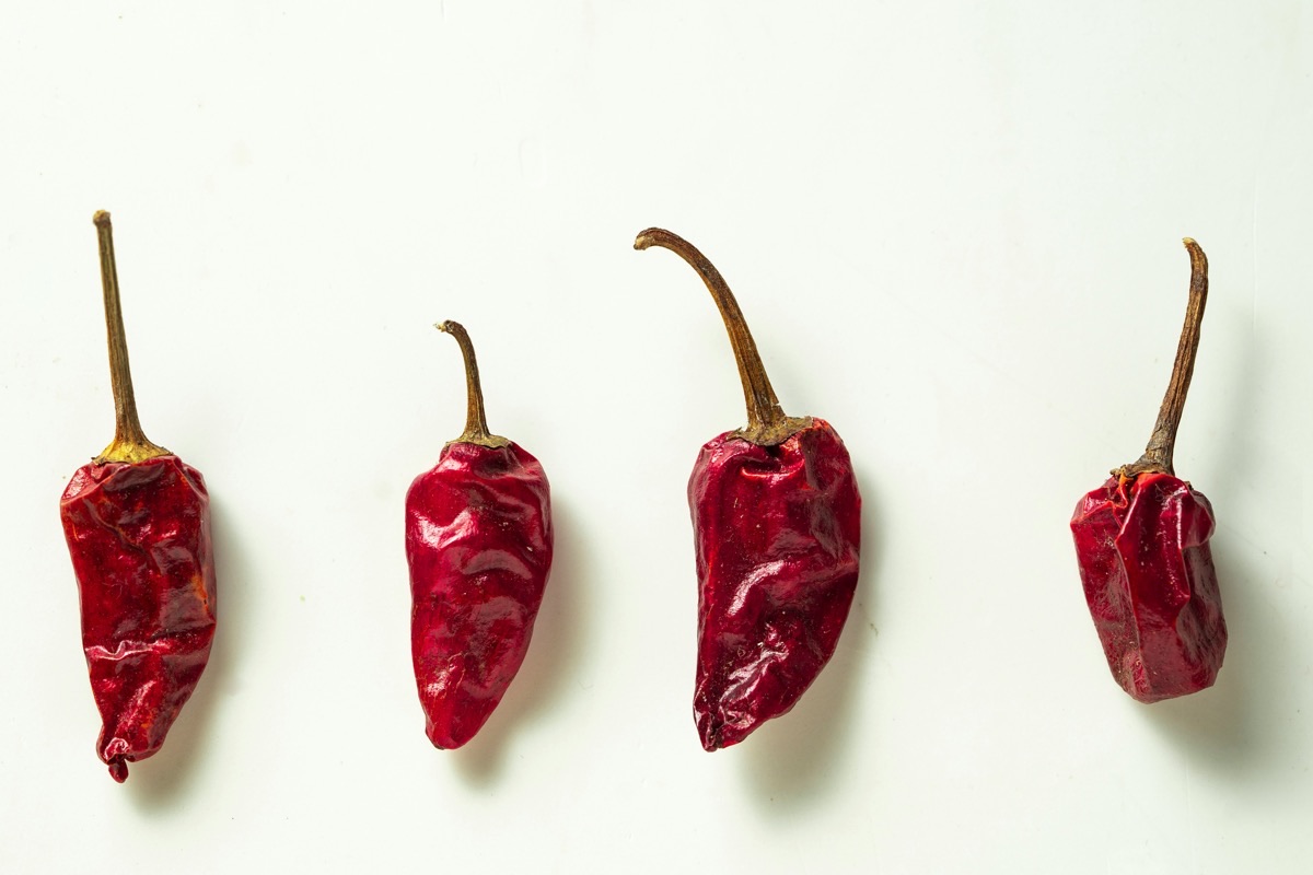 A close-up of a single red chili pepper on a clean white surface