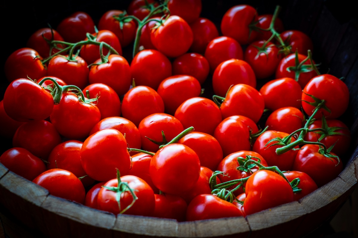 Ripe red vine tomatoes piled in a wooden basket at a market